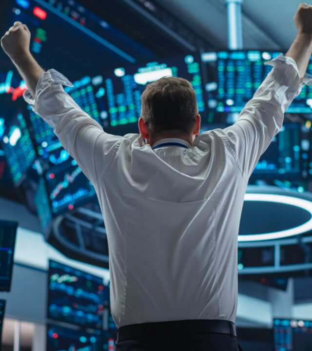 Excited Businessman Raises Hands and Punches Air while Celebrating Successful Deal. Stock Exchange Manager Happy After Investment Day. Broker in White Shirt Wins a Profitable Contract. Back View Excited Businessman Raises Hands and Punches Air while Celebrating Successful Deal. Stock Exchange Manager Happy After Investment Day. Broker in White Shirt Wins a Profitable Contract. Back View